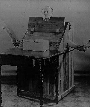 Harry Houdini in a wooden box designed to restrict a medium's movement - headstuff.org
