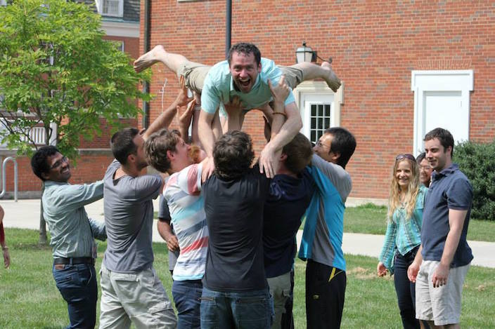 Man being lifted into air by group of people in quad