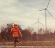 boy running with wind turbines in background